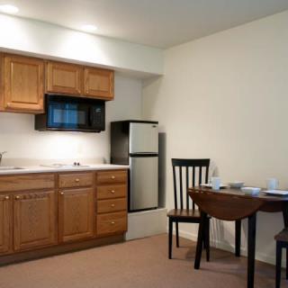 A compact kitchen and dining area featuring wooden cabinets, a microwave, and a small refrigerator.
