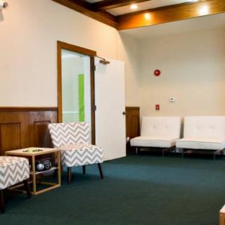An empty waiting room with chairs and a carpeted floor.