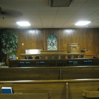Interior view of a quiet church with wooden pews and an altar.