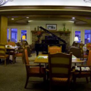 A cozy dining area with a grand piano and comfortable seating.