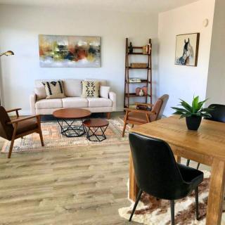 A cozy living room with modern decor, featuring a sofa, coffee table, dining area, and stylish artwork.