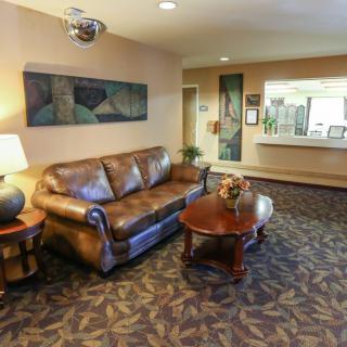 A lobby area featuring a leather sofa, coffee table, and art on the walls, with a reception desk in the background.