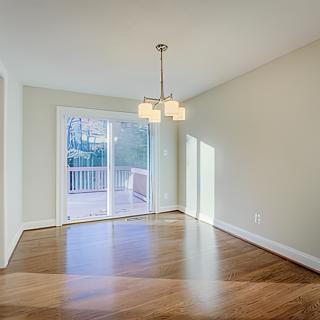 Bright and empty dining room with hardwood floors and a sliding glass door.
