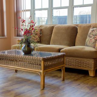 A cozy living room setting with a comfortable sofa and a glass-topped coffee table adorned with a flower arrangement.