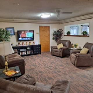 A cozy living room with comfortable recliners, a television, and decorative indoor plants.