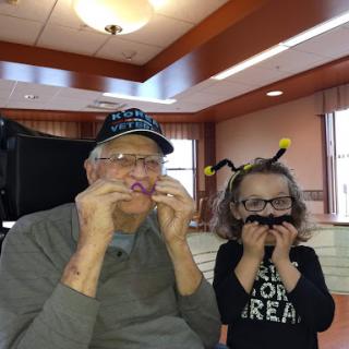 A playful moment between a grandparent and grandchild, both making funny faces.