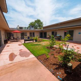 A sunny courtyard with a garden and patio area between buildings.