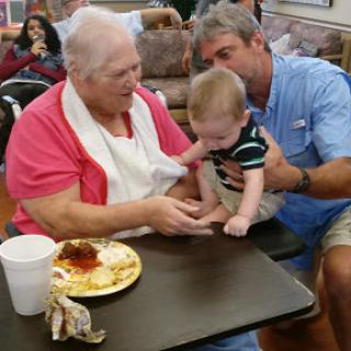 A heartwarming moment shared between a grandmother and her baby as they enjoy time together during a meal.