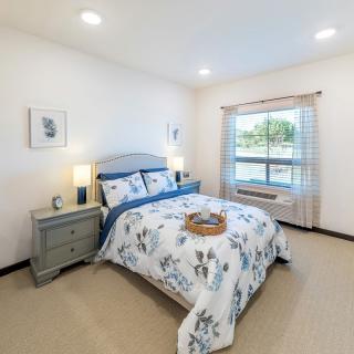 A neatly organized bedroom with floral bedding and ample natural light.