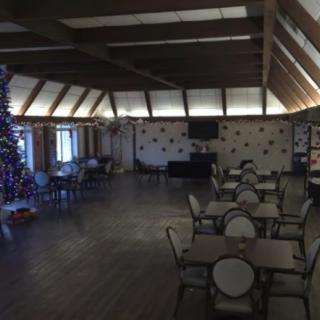 A decorated dining area with tables and chairs, featuring a Christmas tree.