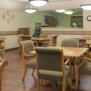 A cozy dining area with wooden tables and chairs, featuring soft lighting.