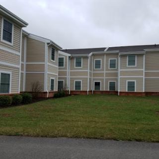 A residential building with a well-maintained lawn under a cloudy sky.