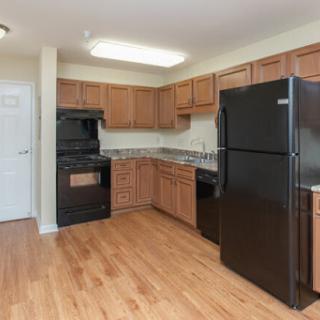 A modern kitchen featuring black appliances, wood cabinets, and granite countertops.