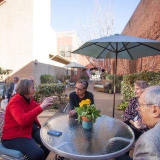 A group of people enjoying a conversation on a sunny patio.