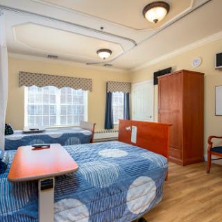 A well-lit hospital patient room featuring two beds and modern furnishings.