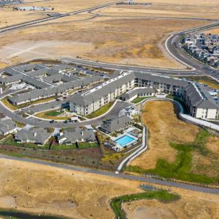 Aerial view of a large housing complex with a swimming pool in a suburban area.