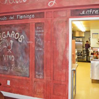 A view of a restaurant entrance with a chalkboard design and adjacent kitchen area.
