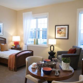 A cozy and well-decorated living space with a bed, armchair, and dining table.