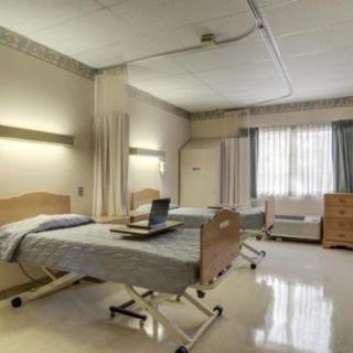 An empty hospital room with two beds and medical equipment.