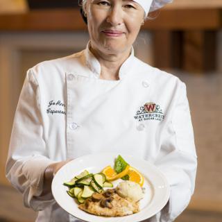 A chef proudly presenting a dish in a restaurant setting.