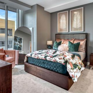 A modern bedroom with stylish decor, featuring a bed with floral bedding and large windows.
