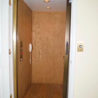 An interior view of an elevator with wooden paneling and control buttons.