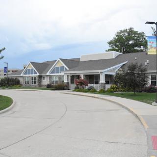 A modern residential building with a landscaped entrance under a cloudy sky.