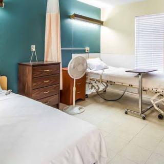 A cozy hospital patient room featuring two beds, a fan, and modern decor.