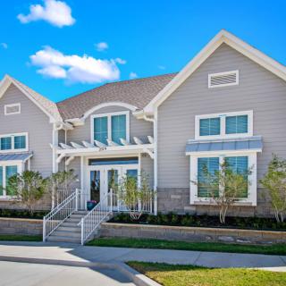 A modern suburban house with a well-maintained front yard and clear blue sky.