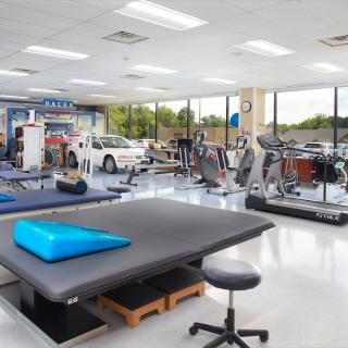 A modern physical therapy room equipped with various exercise machines and therapy tools.