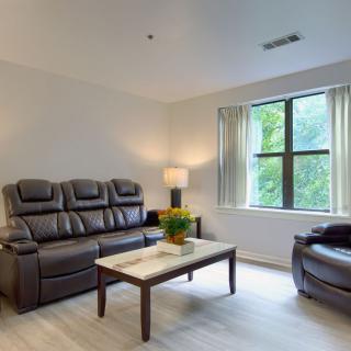 A minimalist living room with a leather sofa, armchair, and a coffee table near a window.