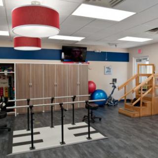 A rehabilitation gym equipped with parallel bars, exercise balls, and stairs for physical therapy.