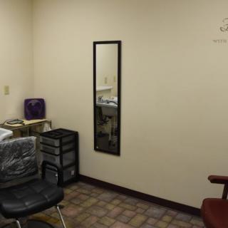 An empty salon with chairs and a mirror, ready for the next client.