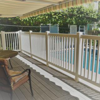 A shaded deck area with a wooden fence overlooking a pool, featuring a chair for relaxation.