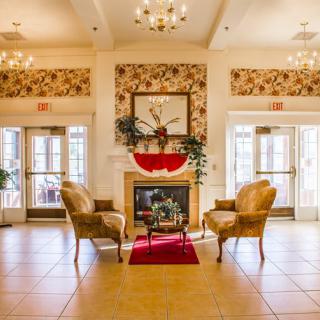 A luxurious lobby with elegant seating around a decorative fireplace, adorned with chandeliers and classic decor.