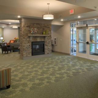A cozy lobby with a stone fireplace, patterned carpet, and seating area.