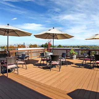 A spacious outdoor deck with tables and chairs under large umbrellas, overlooking a scenic view.