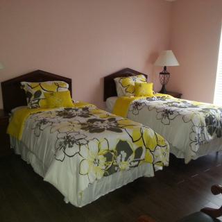 A cozy bedroom with twin beds featuring floral bedding and a lamp.