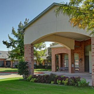 A well-maintained building entrance with brick columns and lush landscaping.