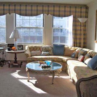A cozy living room with a curved sofa and ample sunlight streaming through large windows.