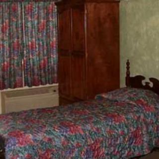 A vintage-style bedroom with a single bed, wardrobe, colorful curtains, and an air conditioner.