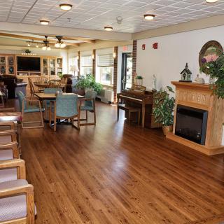 A spacious living room with hardwood floors, featuring a fireplace, piano, and seating area.