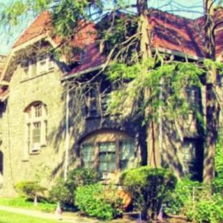 A beautiful stone house surrounded by trees and a lush garden.