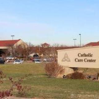A view of the Catholic Care Center with its sign and surrounding landscape.