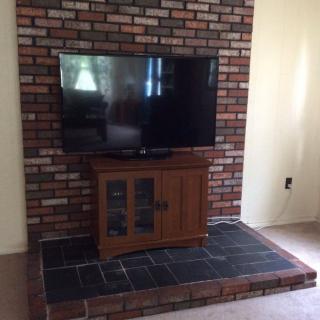 A television on a wooden stand against a brick wall in a living room.