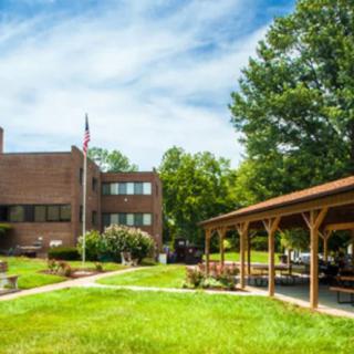 A brick building with a manicured lawn and trees under a blue sky.