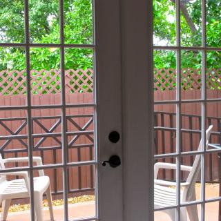 View of a cozy patio area with chairs, seen through glass doors on a bright day.