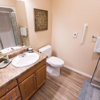 A modern bathroom featuring a sink, toilet, shower, and elegant wooden cabinetry.