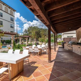 Outdoor patio with seating area and wooden pergola on a sunny day.