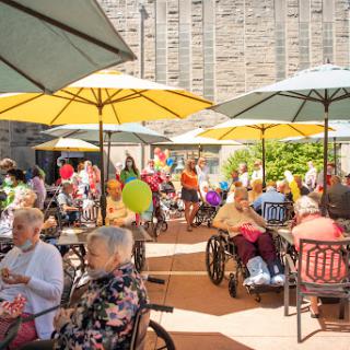 A vibrant outdoor gathering of senior citizens enjoying a sunny day under colorful umbrellas.